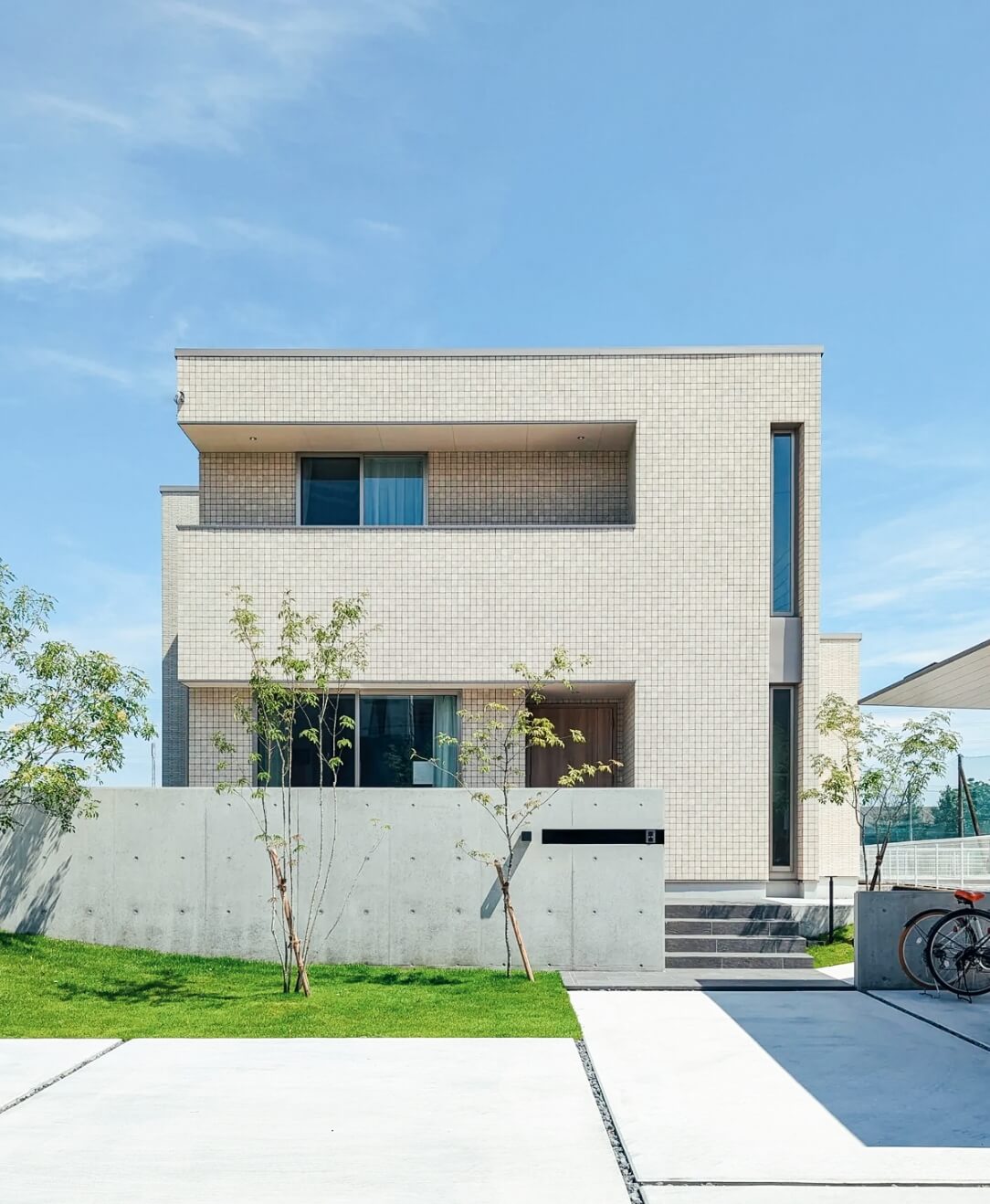 広い駐車場のある2階建の白を基調とした家