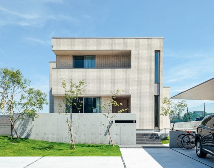 広い駐車場のある2階建の白を基調とした家