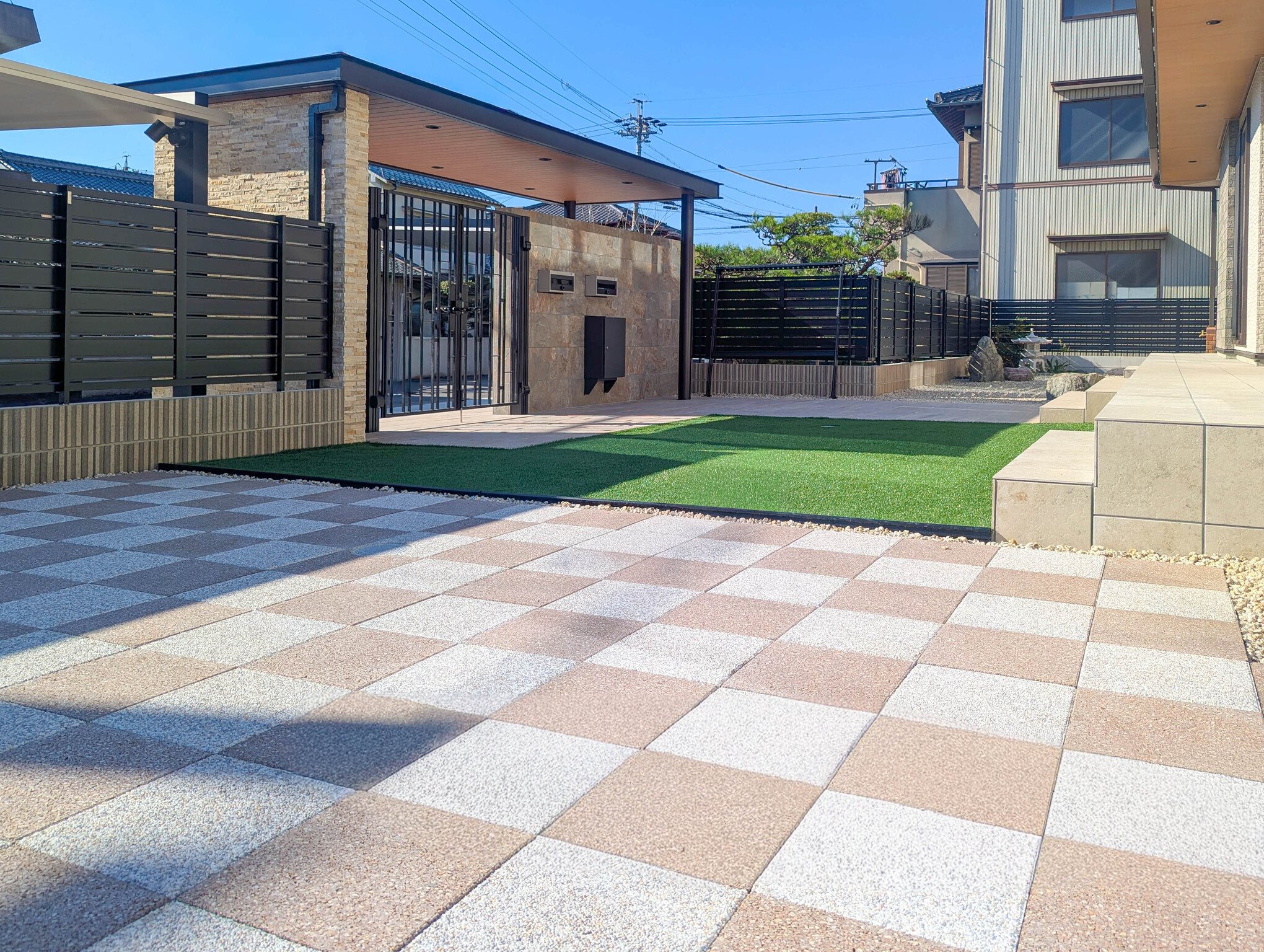 愛知県あま市 人工芝と透水性の高いコンクリート平板を採用した市松模様のアプローチが広がるお庭。